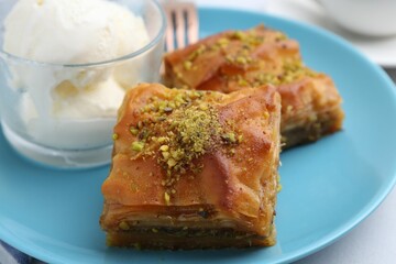 Tasty baklava with chopped nuts and scoops of ice cream on table, closeup