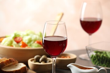 Red wine and delicious dinner served on table, closeup