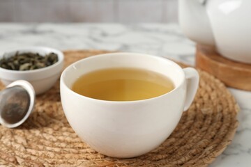 Refreshing green tea in cup on white marble table, closeup