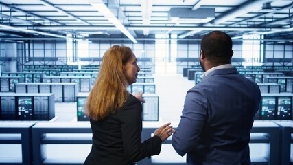 Teamworking admin colleagues inspecting server room hardware. IT expert and colleague supervising...