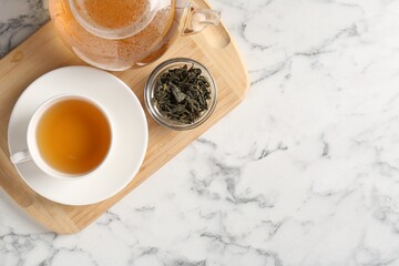 Refreshing green tea and dry leaves on white marble table, top view. Space for text