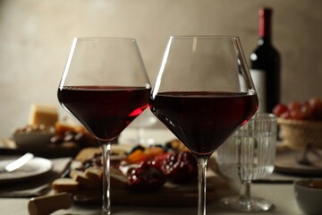 Red wine and different snacks served on table, closeup