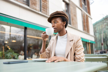 Urban black woman enjoying a coffee outdoors in city cafe