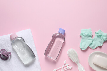 Baby oil and bath accessories on light pink background, flat lay. Space for text