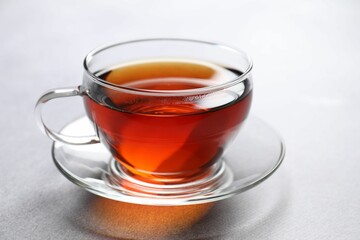 Aromatic black tea in cup on light table, closeup