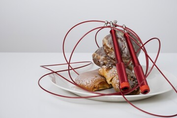 A plate of bakery with a red jump rope creatively arranged around them. This composition symbolizes...