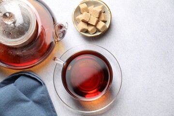 Aromatic black tea and brown sugar cubes on light table, flat lay