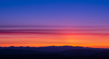 Fototapeta premium Vibrant Sunset Over Silhouetted Mountain Range