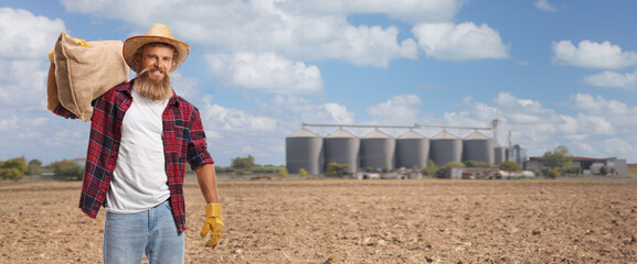 Silos on a field and a young bearded farmer