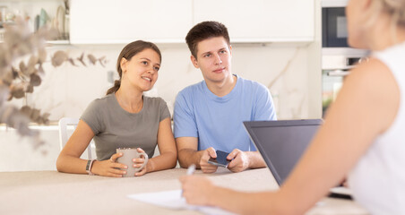 Woman manager tells young girl and guy to clients about tourist hotel. Customers discuss with manager terms of delivery and warranty cases of equipment maintenance