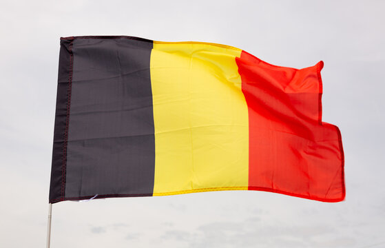 Big flag of Belgium fastened on stick against background of blue sky under daylight
