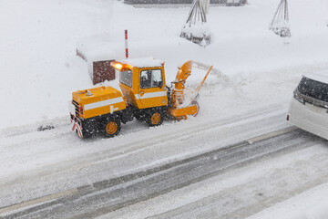 雪道の道路を除雪する小型のロータリー除雪車