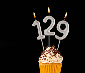 Number 129 shaped candles - Birthday cupcake on black background.