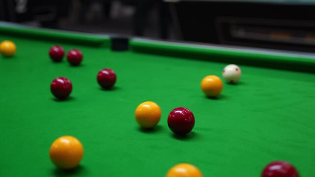 the break of red and yellow blackball Pool balls in a triangle on a green cloth pool table, hit by the cue pocketing a red ball with sound