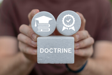 Person holding blocks sees word: DOCTRINE. Doctrine business concept. Doctrine - body of teachings or instructions, taught principles or positions, as the essence of teachings in a belief system.