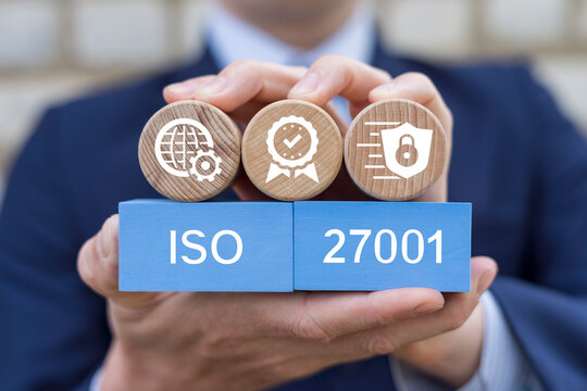 Man holding blocks with icons sees text: ISO 27001. ISO 27001 Standard certification standardisation quality control concept. ISO 27001 certified for information security management system (ISMS).