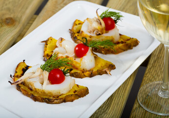 Sepia fried on a grill with pineapple and cherry tomatoes is tasty dish in the kitchen.
