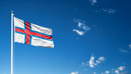 Fototapeta premium national flag of Far Oer waving against blue sky, official flag of the nation, blowing in the wind 