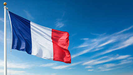 Naklejka premium national flag of France waving against blue sky, official flag of the nation, blowing in the wind 