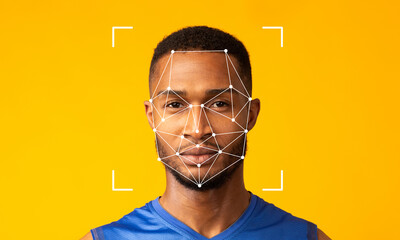 A man poses against a vibrant yellow background while facial recognition technology is applied to his face. The geometric overlay illustrates digital identification features.