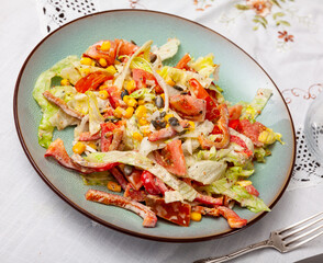 There is salad of chopped fresh vegetables on plate. Dish is made from salad pim , cabbage, bell pepper, corn and seasoned with mayonnaise