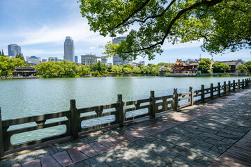 The waterfront of Moon Lake Park in Ningbo, Zhejiang, China. A paved pathway winds along the...