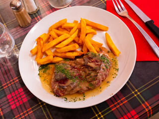 Beef steak on plate with fries on side and gravy