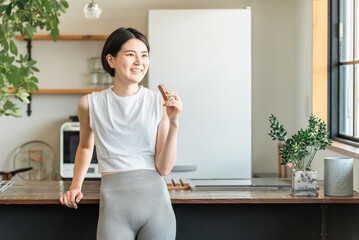 プロテインバー・栄養バーを食べるヨガウェア姿の若いアジア人女性
