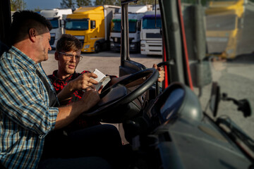 Truck driver having conversation with fleet manager before the trip, looking at paperwork 