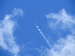 青空を上昇する白い飛行機と飛行機雲