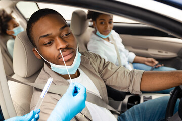 Black Family Getting Tested For Coronavirus Sitting In Car, Wearing Face Masks At Drive-Thru Covid-19 Testing Site. Coronavirus Diagnostic, Traveling And Tourism In Pandemic Concept