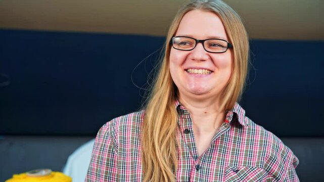 Portrait of positive woman in glasses with long hair, respondent at interview, embarrassed by awkward delicate questions, nervously straightens hair, flirts feignedly, laughs it off Blogger broadcast