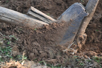 Old wooden plough in the field. It is used to prepare the soil in traditional farming. A sturdy wooden plough, cuts a furrow through the rich earth. guides the sharpened iron tip, turning the soil for
