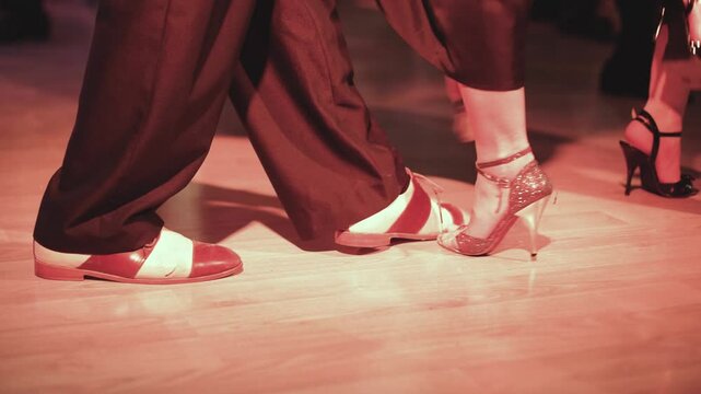 Couples dancing traditional latin argentinian dance milonga in the ballroom, tango salsa bachata kizomba lesson in red and purple lights, evening dance school class festival, performance rehearsal
