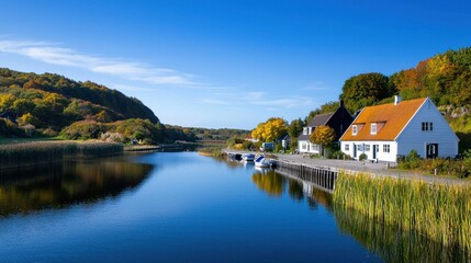 Fototapeta premium Serene riverside view with charming houses and autumn foliage.