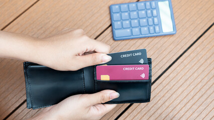 Hand takes out black and red credit card from black wallet
