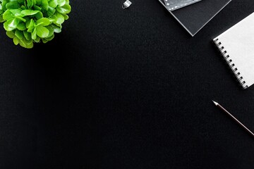 a black table, seen from above , with stationery work materials on the bottom side, on the left...