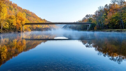 Fototapeta premium Serene autumn landscape with a bridge over a misty river.