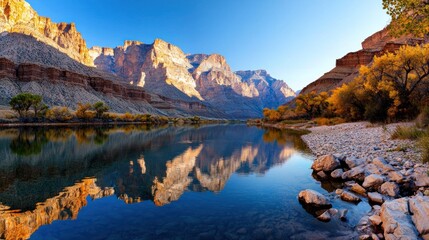 Fototapeta premium Tranquil river reflecting majestic mountains at sunrise.