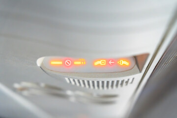 Airplane seat belt and no smoke signals showing the importance of the safety.