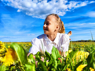 A cheerful child enjoys a sunny day among vibrant dandelions in a lush green field beneath a bright...