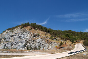 road around rock mountain with steep path warning sign, concrete road curve around mountain slope...