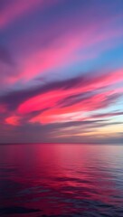 Naklejka premium The sky bursts into a vibrant symphony of colors, a canvas painted with hues of rose, magenta, and fiery orange. The sun, a fiery orb, dips below the horizon, casting long shadows across the tranquil 