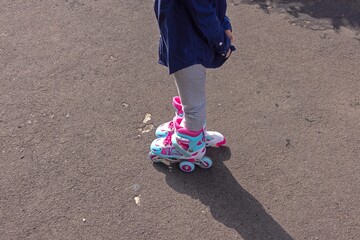 Side view of a little girl's feet wearing roller skates outdoors