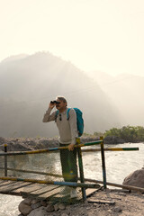 Fototapeta premium Senior man looking through binoculars on wooden walkway