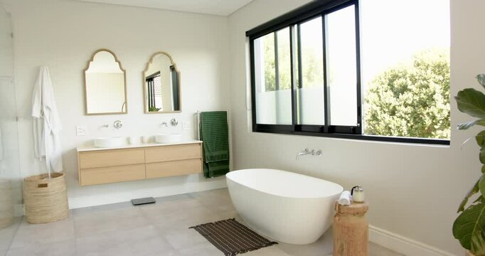 Modern bathroom with freestanding bathtub, double sink vanity, and large window, copy space