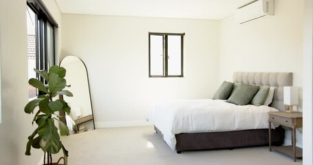 Modern bedroom with large mirror, potted plant, and neatly made bed, copy space