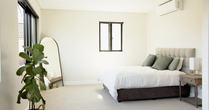 Modern bedroom with large mirror, potted plant, and neatly made bed, copy space