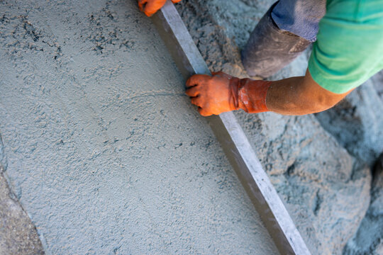 construction workers pouring and smoothing concrete driveway