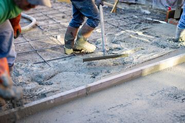 construction workers pouring and smoothing concrete driveway
